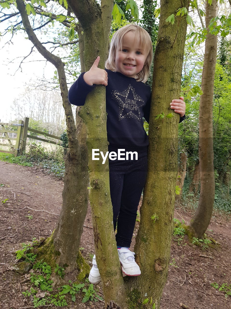PORTRAIT OF GIRL STANDING AGAINST TREE