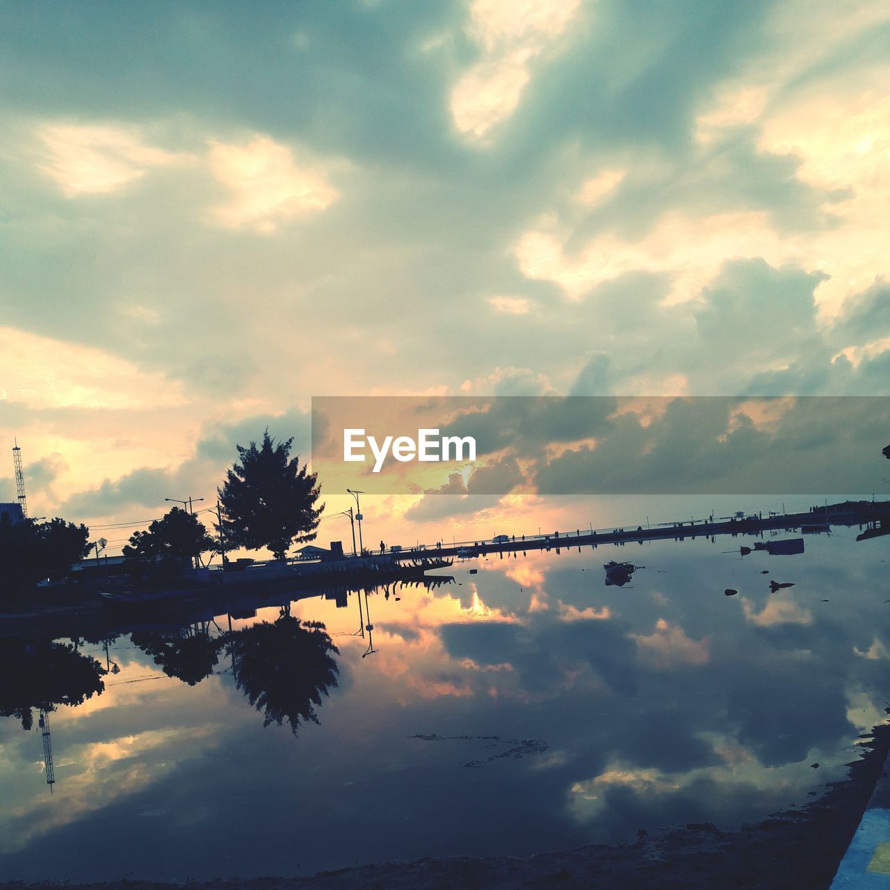 REFLECTION OF TREE IN LAKE AGAINST SKY AT SUNSET