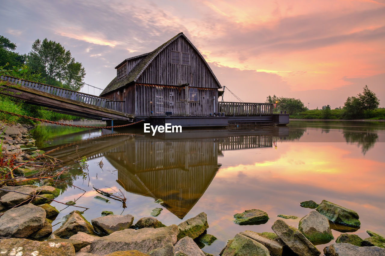 Reflection of building on lake against sky during sunset