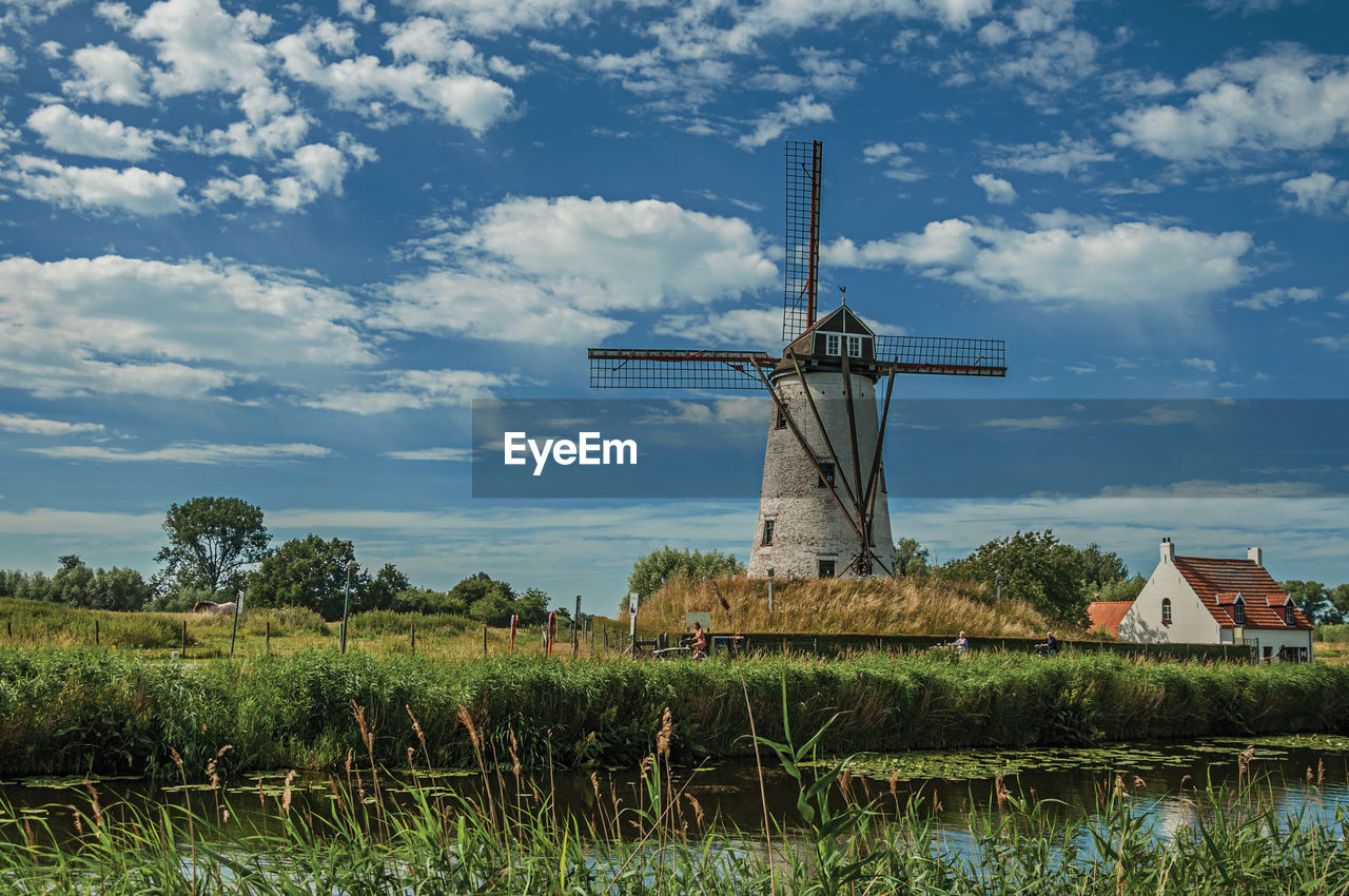 Canal with old windmill and bushes near damme. a charming country village in belgium.