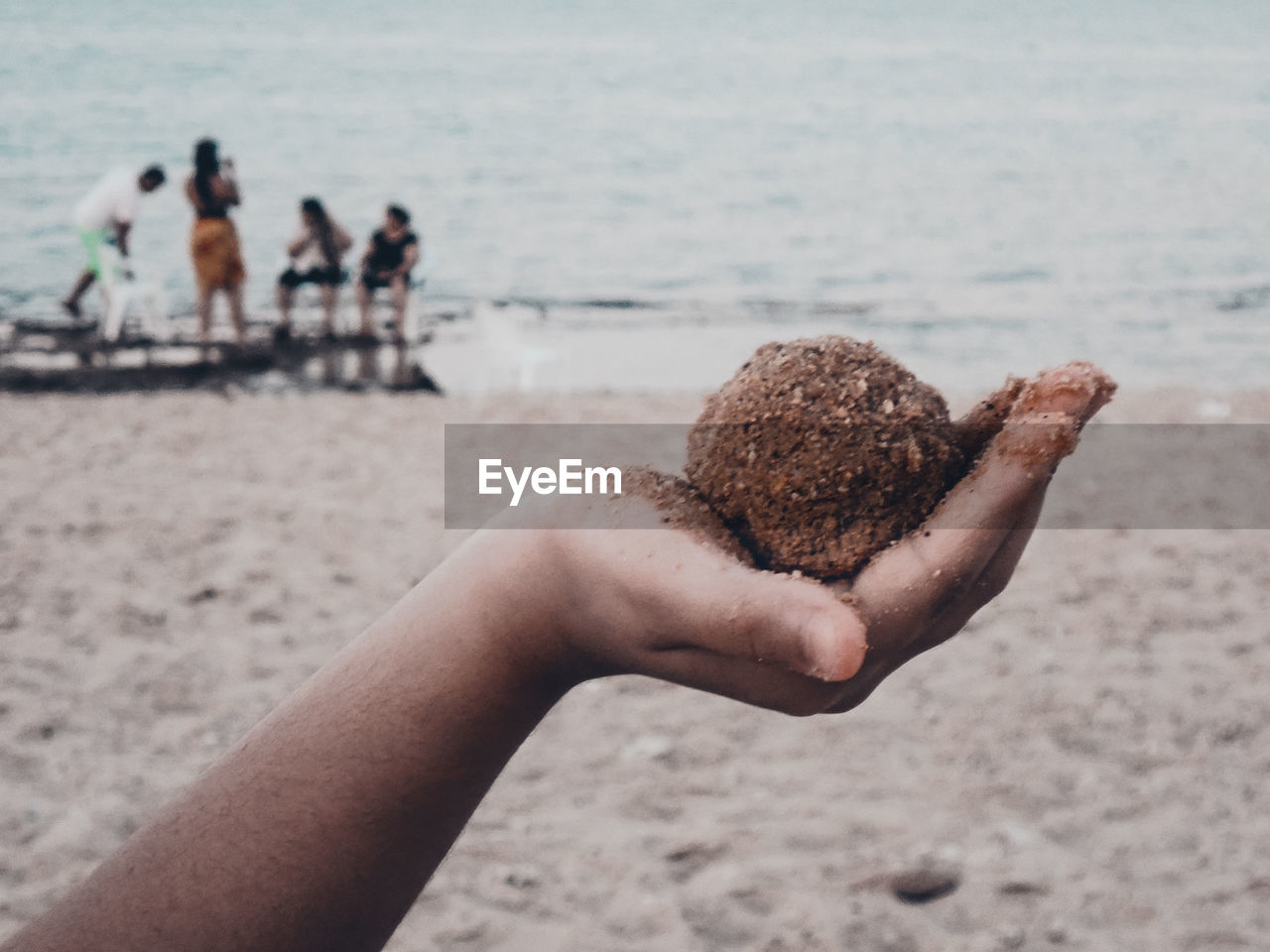 REAR VIEW OF PEOPLE HAND ON BEACH