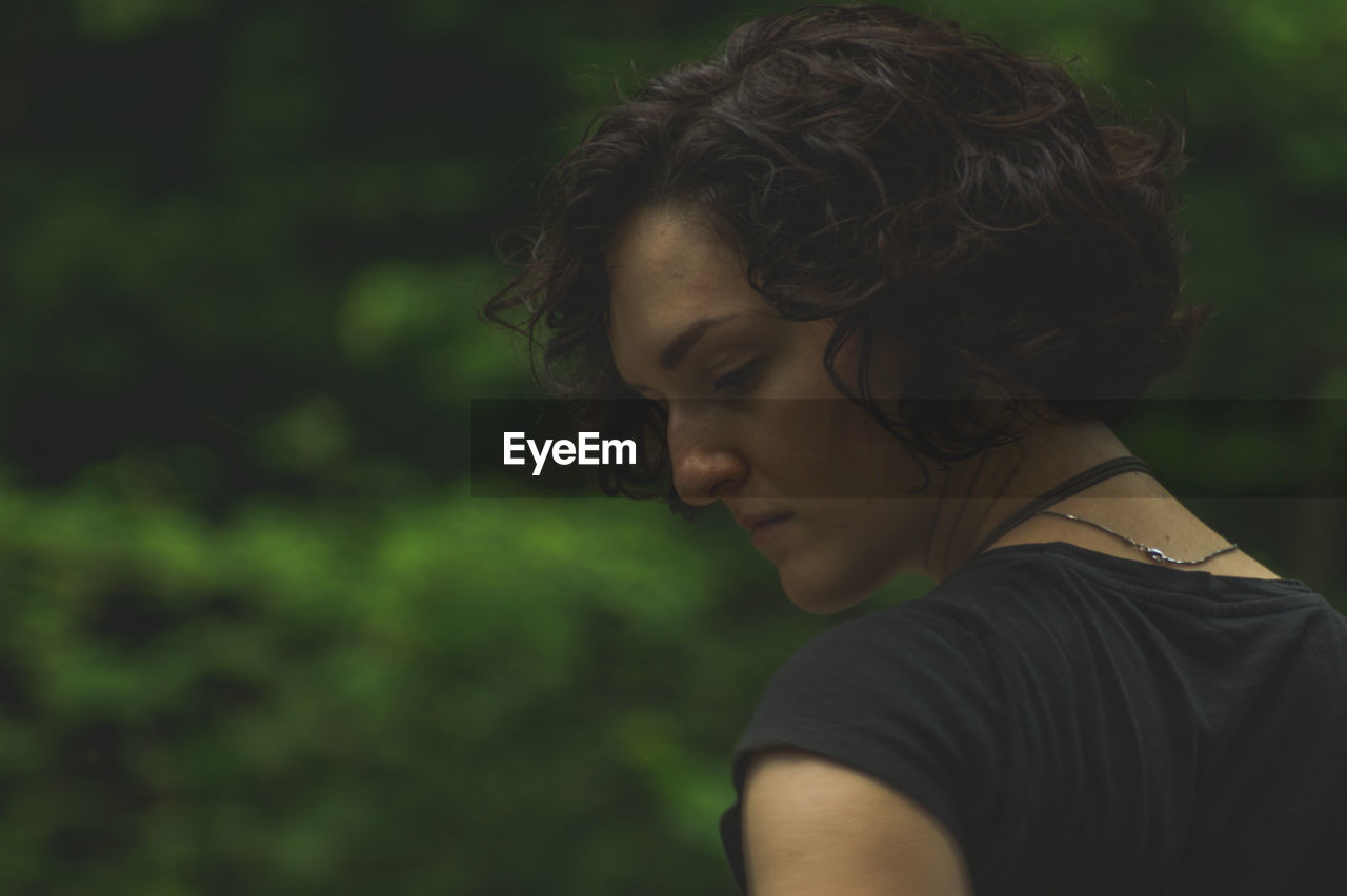 Close-up of thoughtful woman looking down against tree