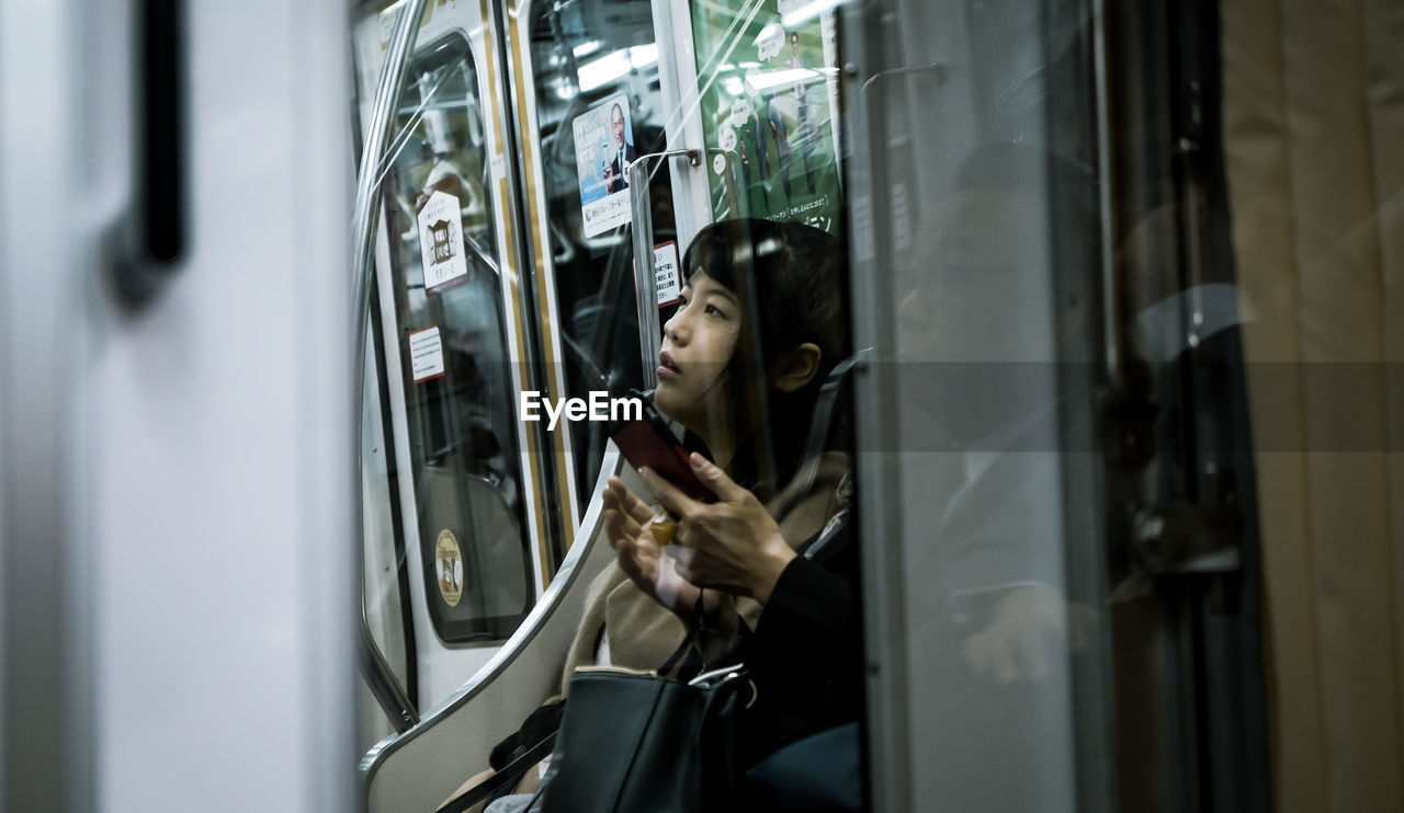 Young woman looking away sitting in subway train