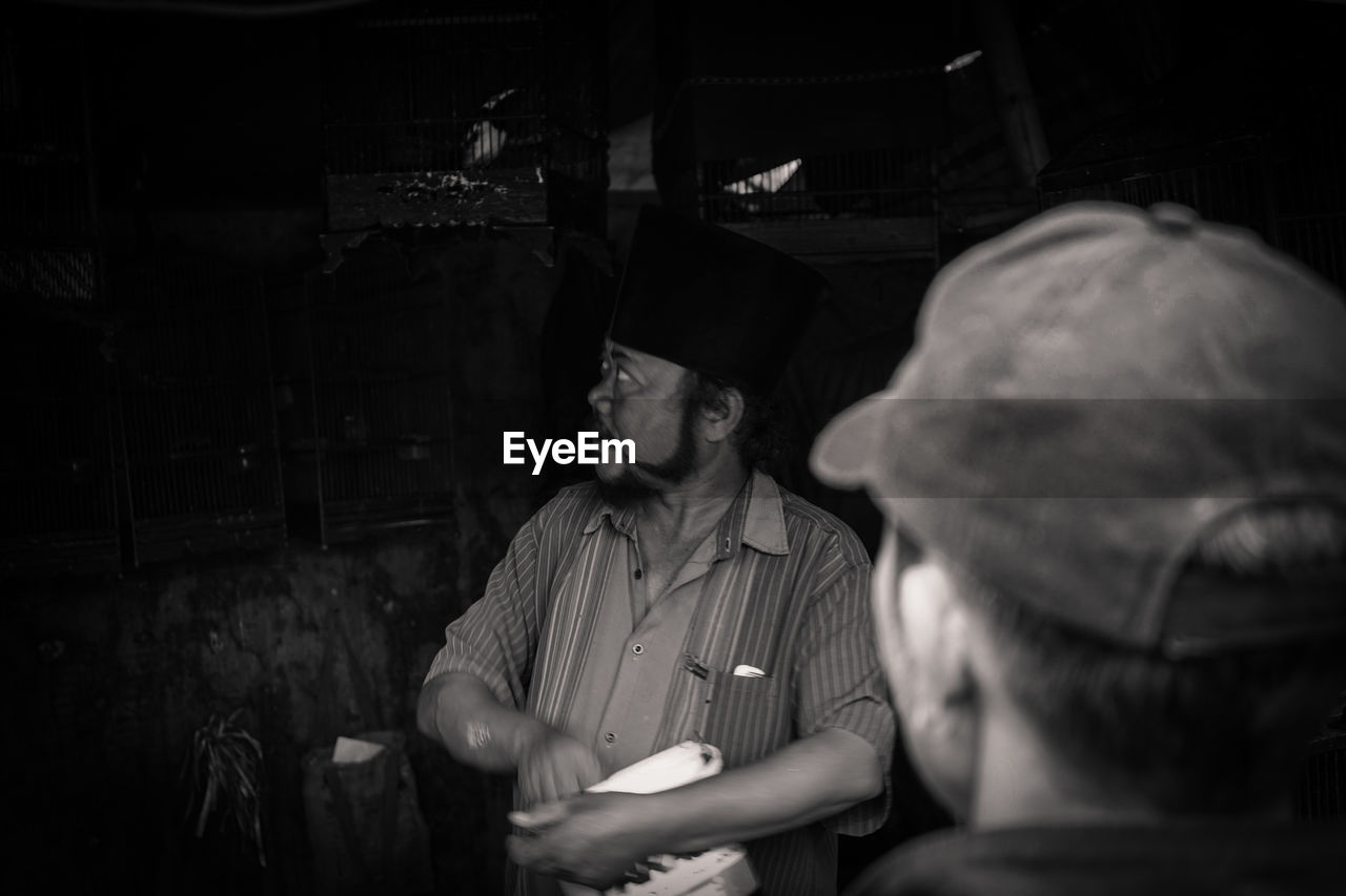 Man wearing hat looking at birdcages