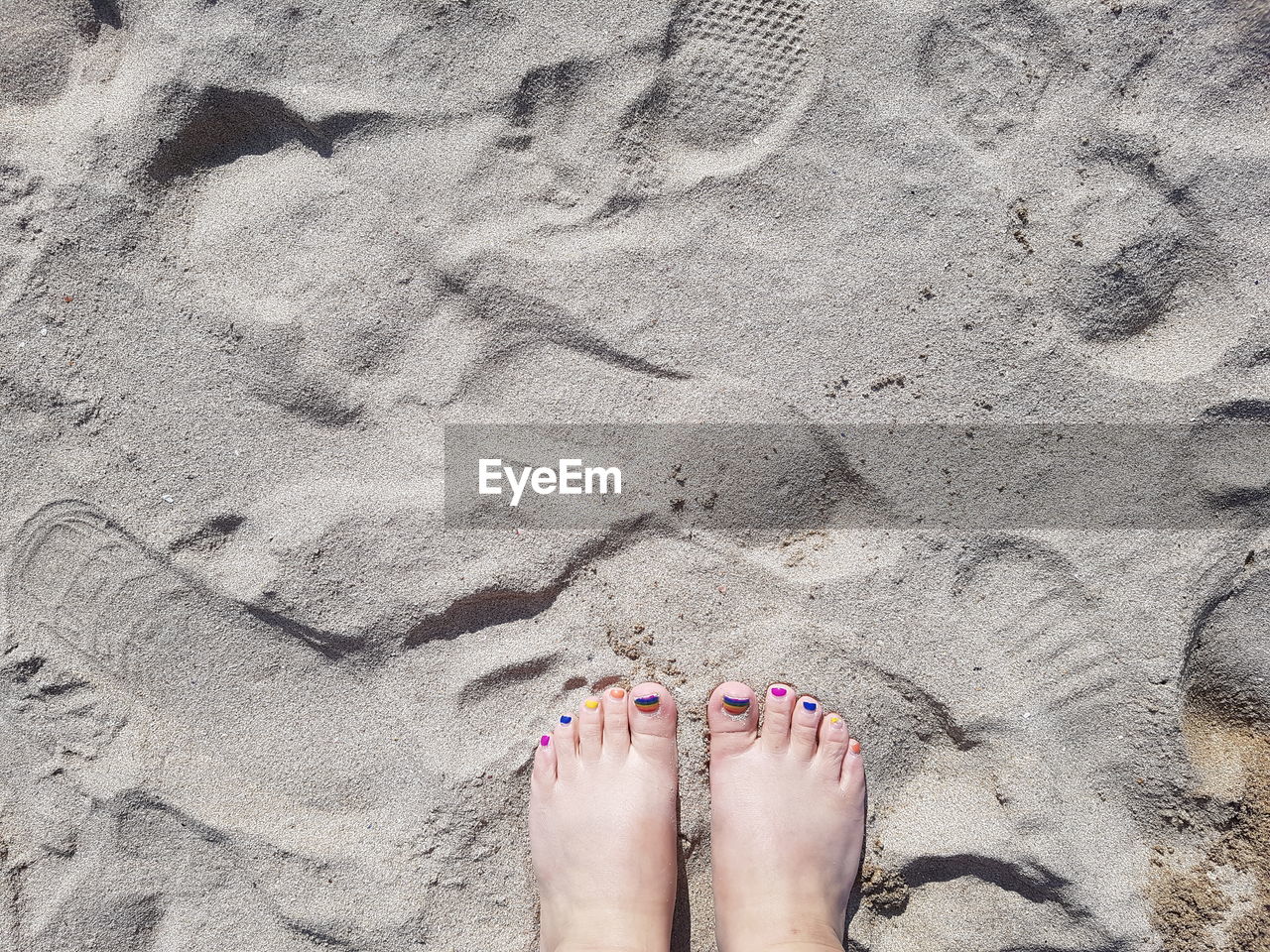 Low section of woman standing on sand