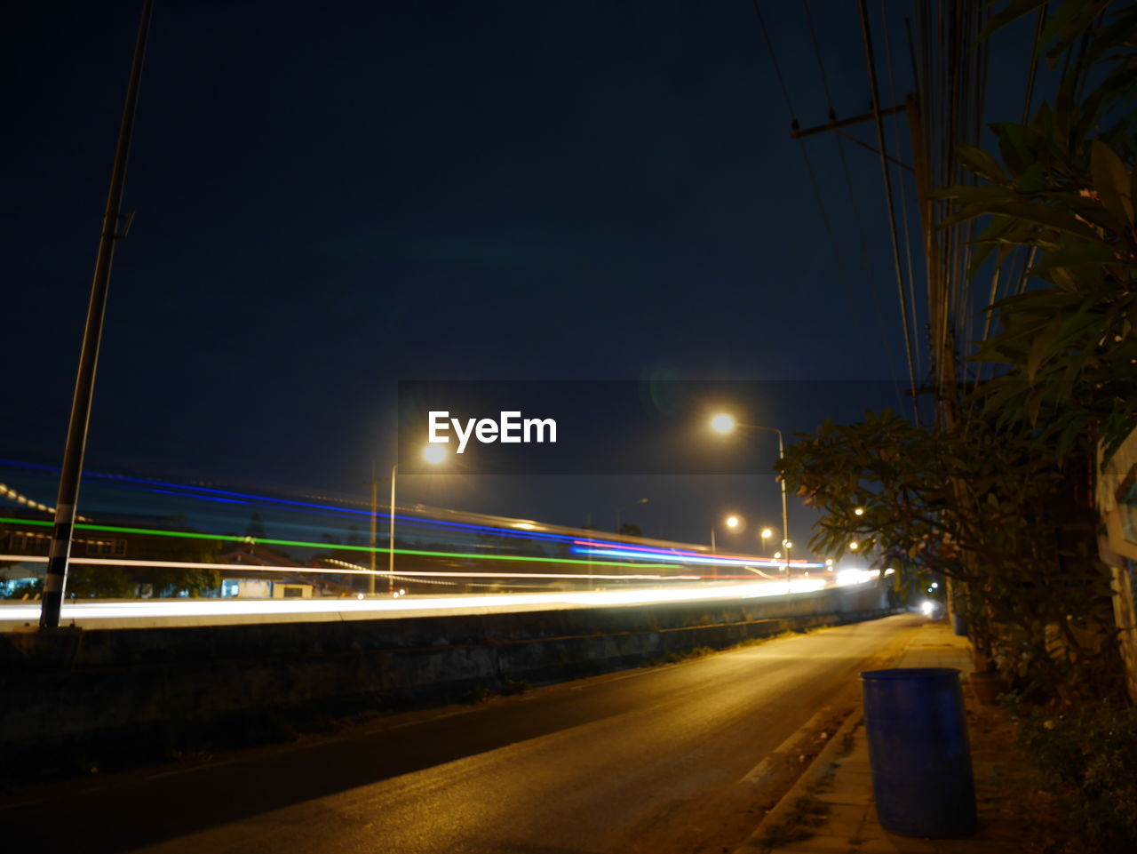 LIGHT TRAILS ON ROAD AGAINST SKY AT NIGHT