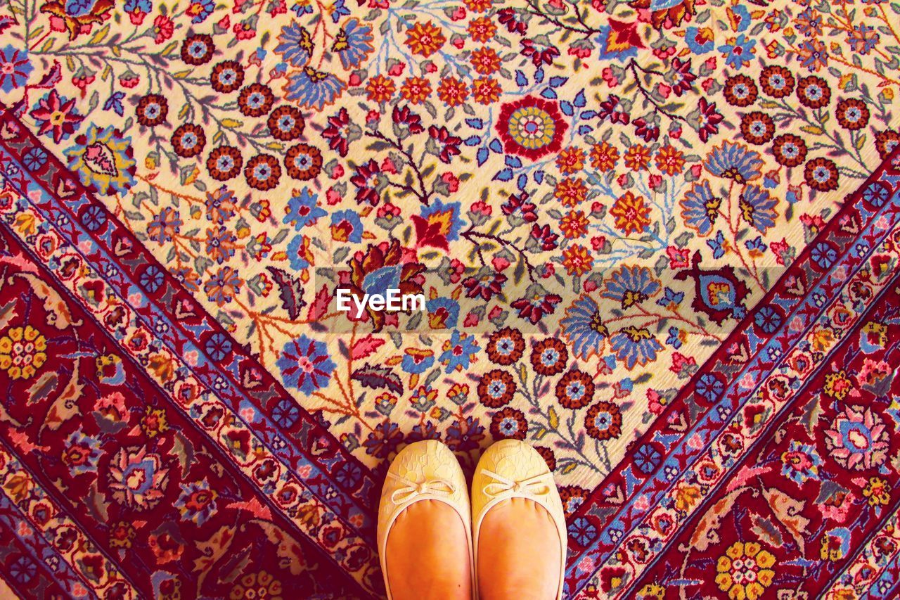 Low section of woman wearing shoes while standing on carpet