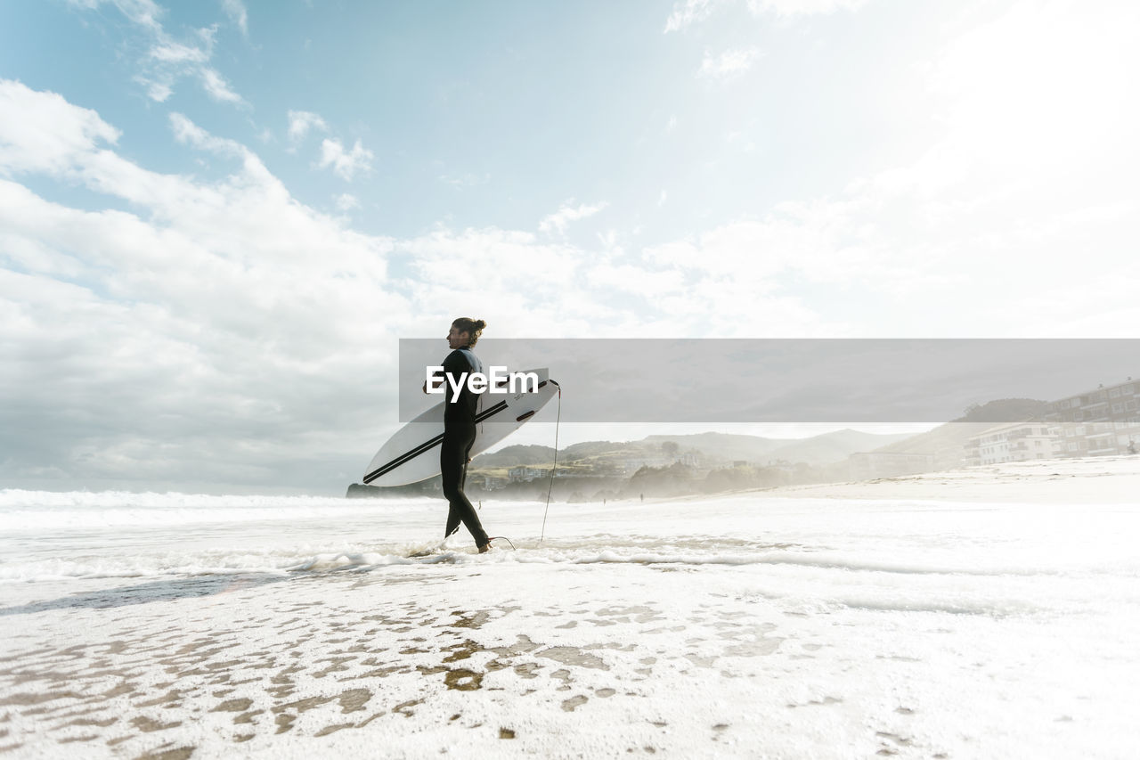 Surfer entering the water in the basque country, spain, bilbao