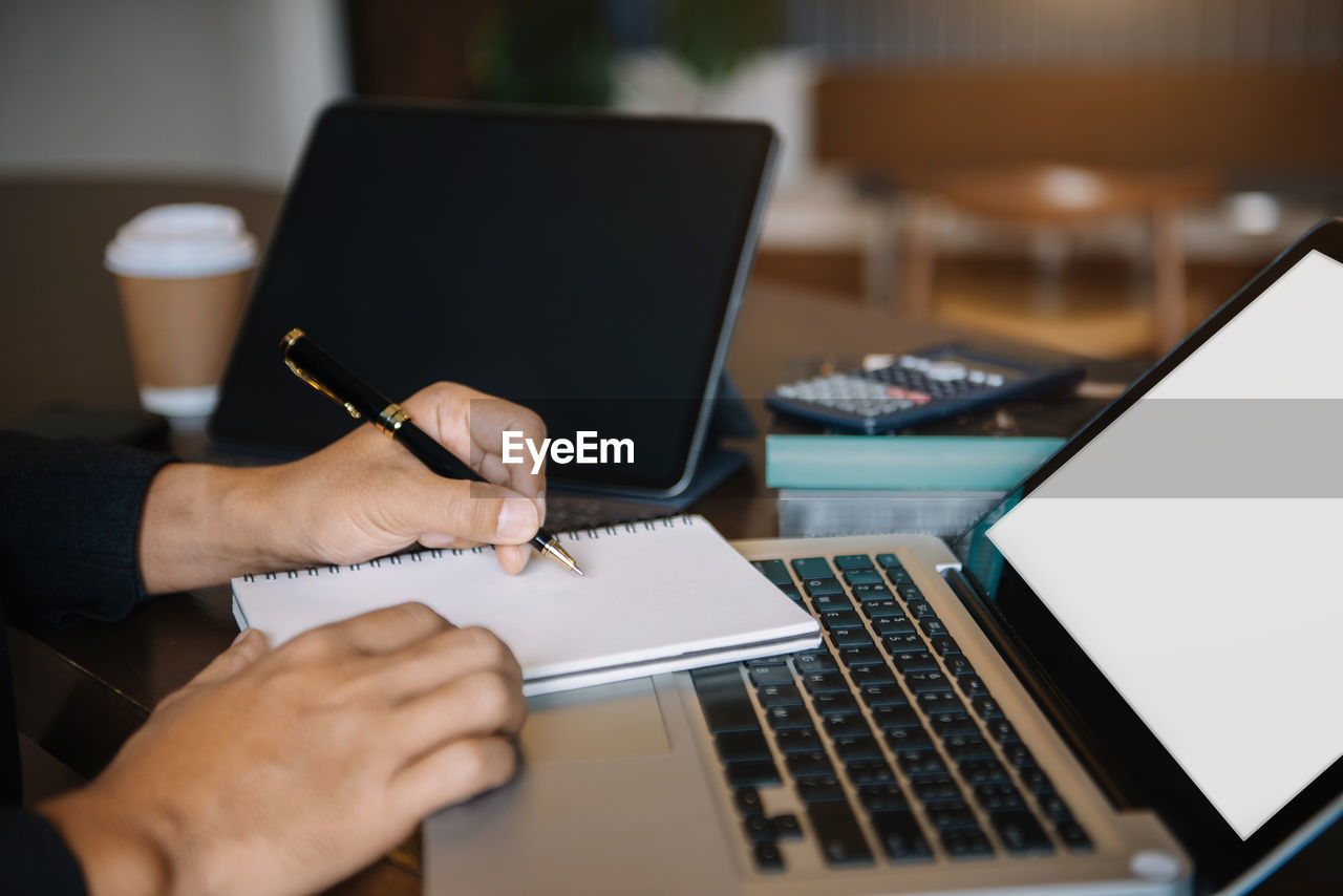 cropped hands of woman using laptop on table