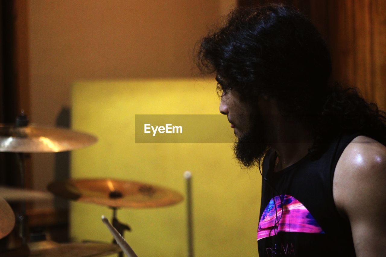 Bearded man playing drums at home