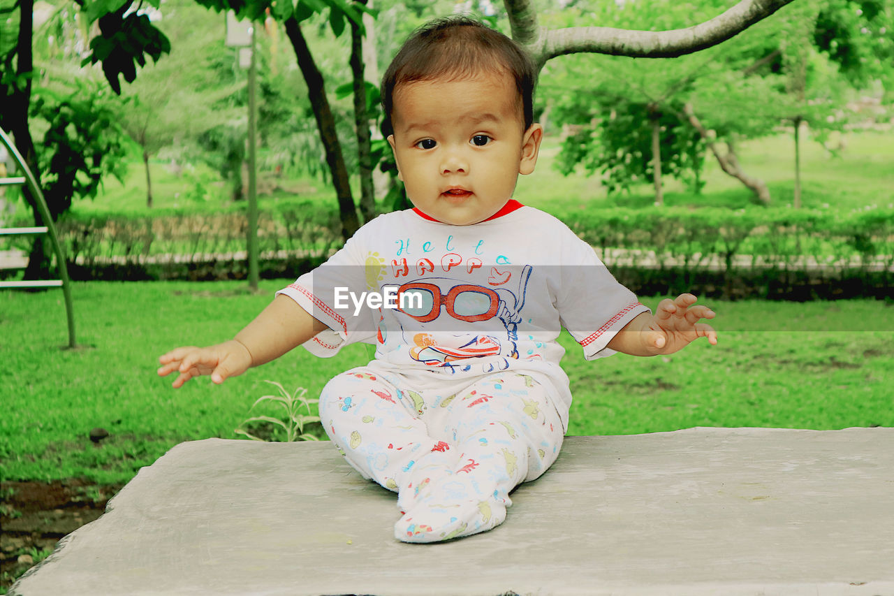 Portrait of cute baby boy sitting on footpath