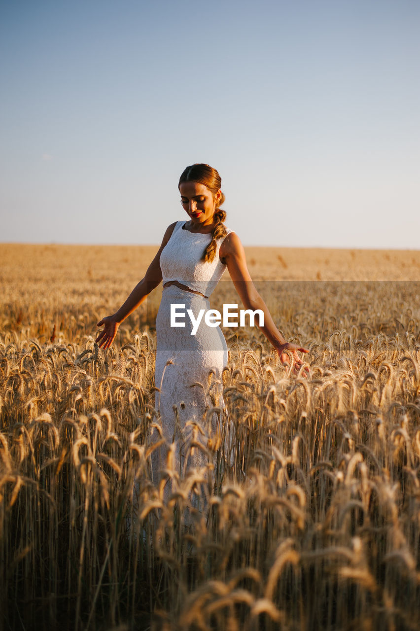 Bride standing amidst cereal plants on agricultural field