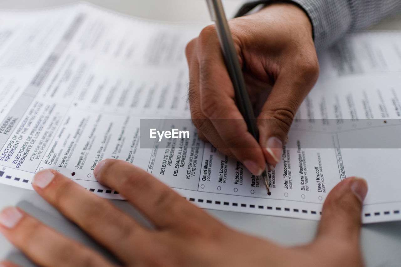 Close up of man's hands completing absentee ballot for election