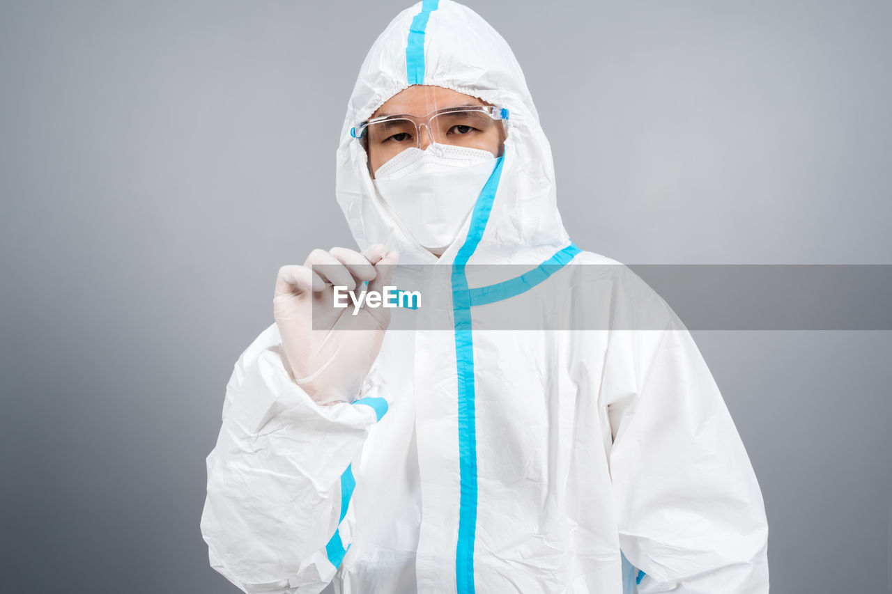 female doctor holding dentures while standing against white background