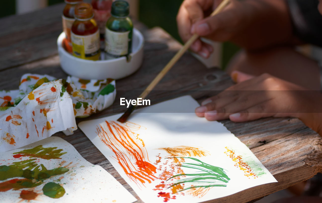 High angle view of hand painting in paper on table