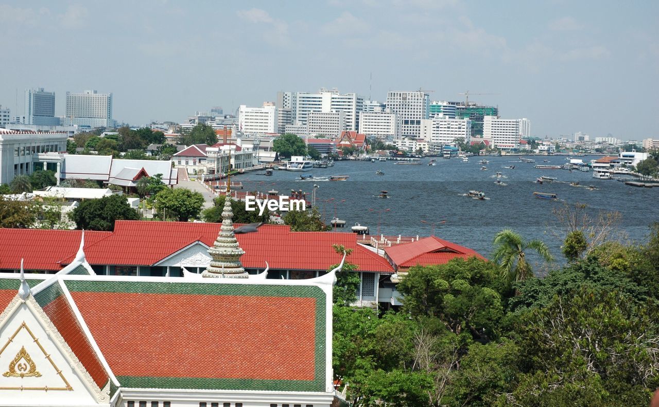 Temple in city by chao phraya delta river against sky