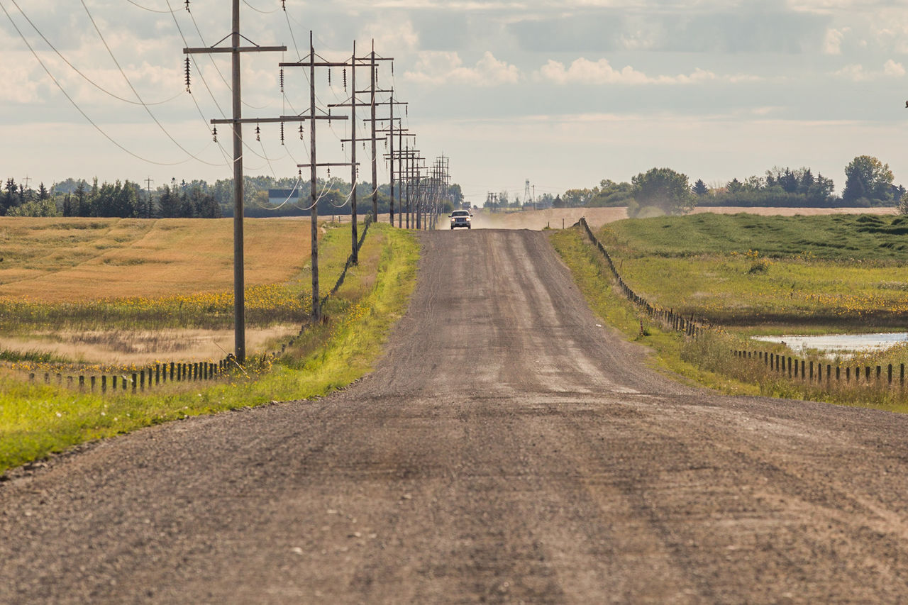 Road amidst field against sky