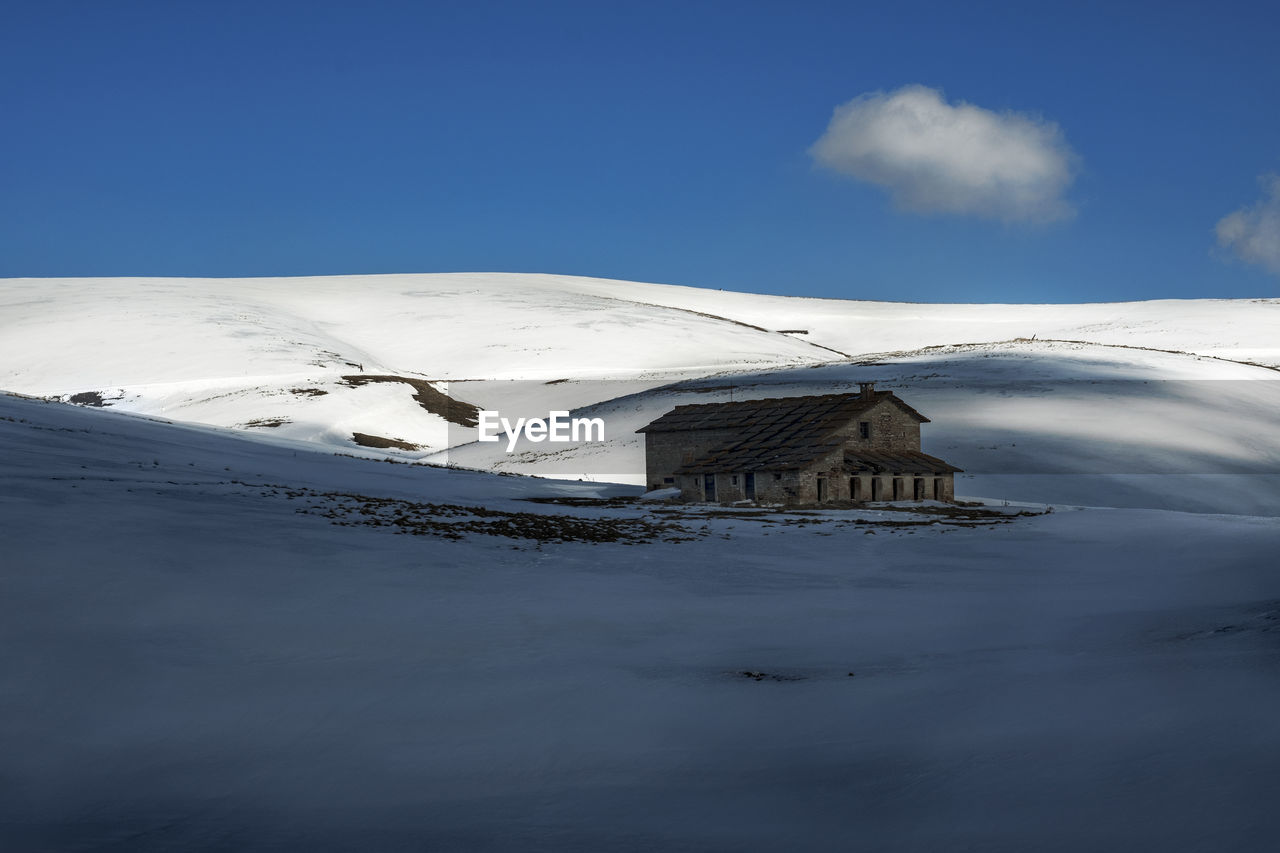 House on snow covered landscape against clear sky