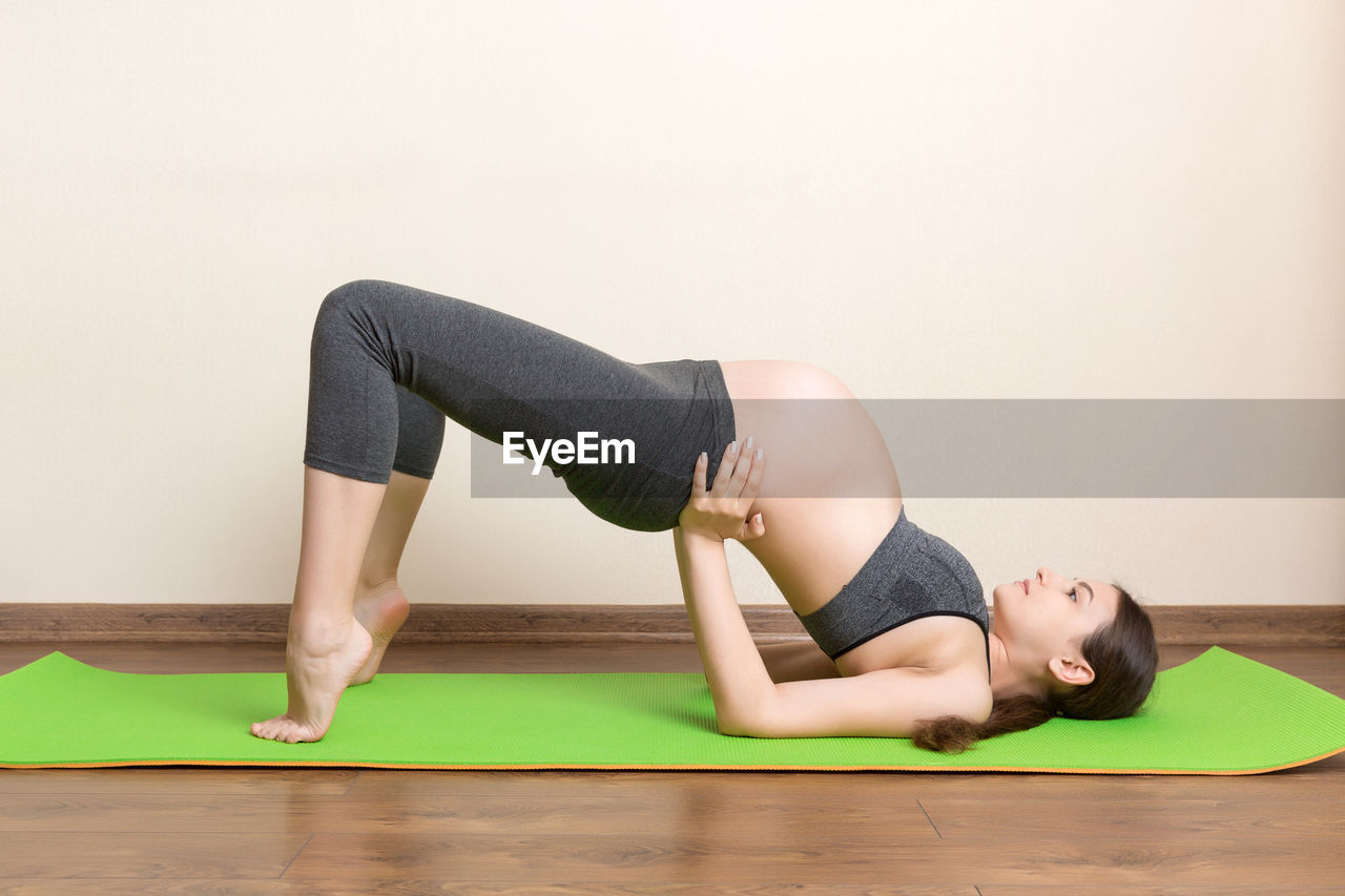 FULL LENGTH OF YOUNG WOMAN LYING ON FLOOR