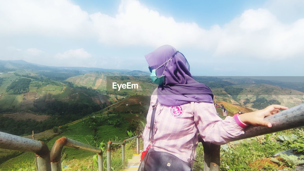 MIDSECTION OF WOMAN AGAINST MOUNTAIN PEAK