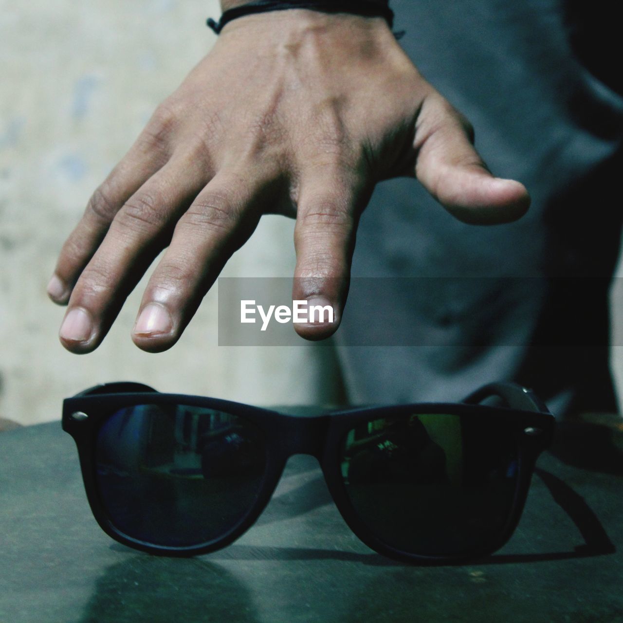 CLOSE-UP OF HAND HOLDING SUNGLASSES AT HOME