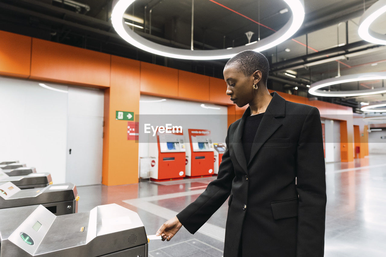 Young woman taking ticket from machine at metro station