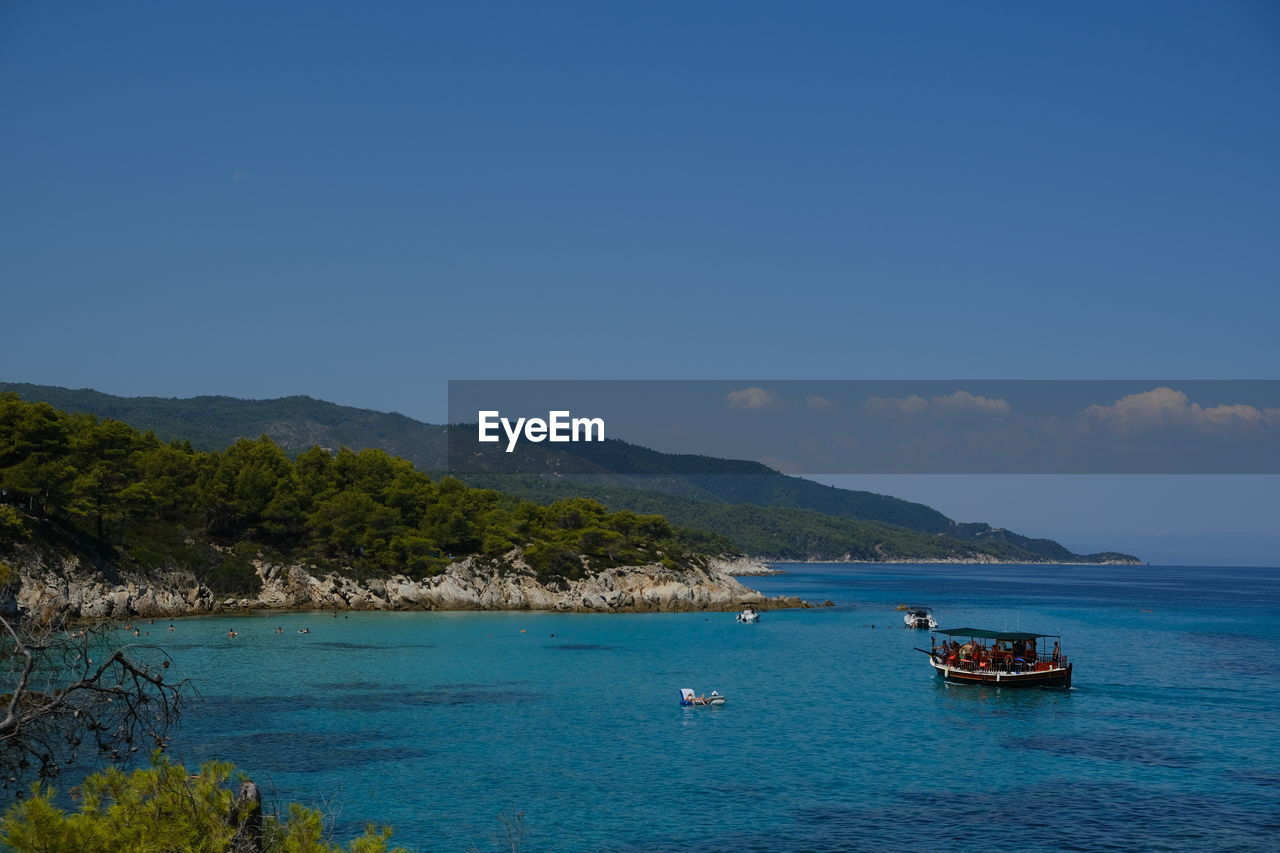 water, sea, nautical vessel, transportation, sky, land, nature, scenics - nature, mode of transportation, travel, blue, body of water, beach, mountain, beauty in nature, travel destinations, shore, tree, ocean, tourism, tranquility, holiday, clear sky, no people, island, coast, vacation, trip, tranquil scene, vehicle, environment, day, plant, ship, coastline, outdoors, landscape, bay, sailing, idyllic, bay of water, horizon, tropical climate, cove, non-urban scene, seascape, sunny, sailboat, boat, yacht