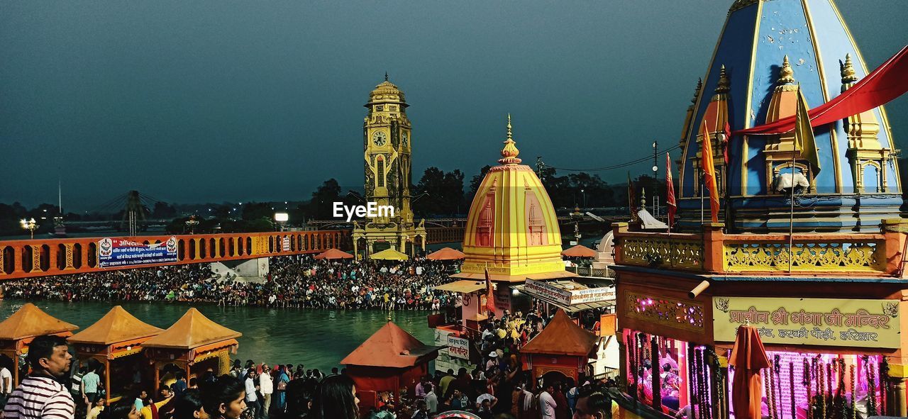 architecture, built structure, building exterior, travel destinations, city, night, crowd, group of people, travel, religion, large group of people, sky, building, tourism, illuminated, nature, belief, place of worship, landmark, history, evening, outdoors, the past, spirituality, cityscape, amusement park, city life, tradition