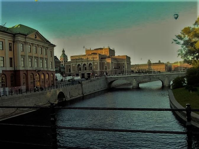 BRIDGE OVER RIVER WITH BUILDINGS IN BACKGROUND