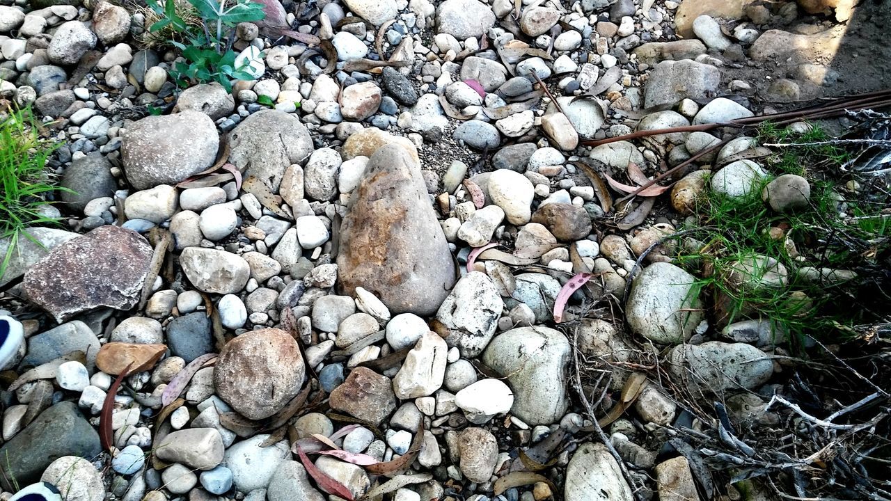 HIGH ANGLE VIEW OF PEBBLES ON BEACH