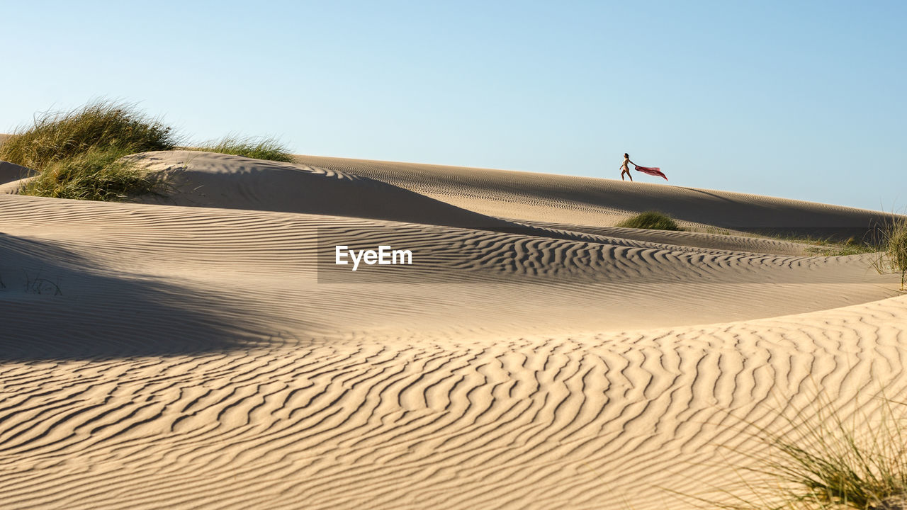 Distant view of woman walking on desert