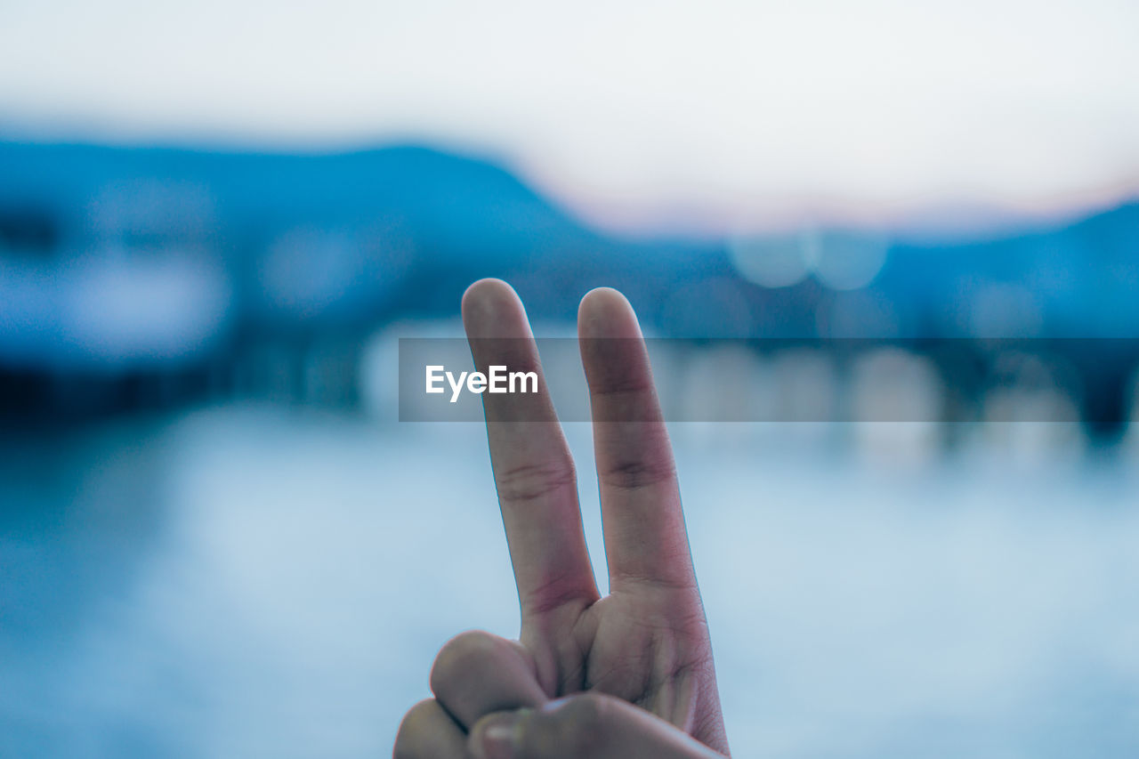 Cropped hand gesturing at beach