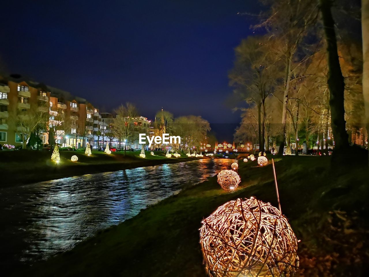 ILLUMINATED CITY BY LAKE AGAINST SKY