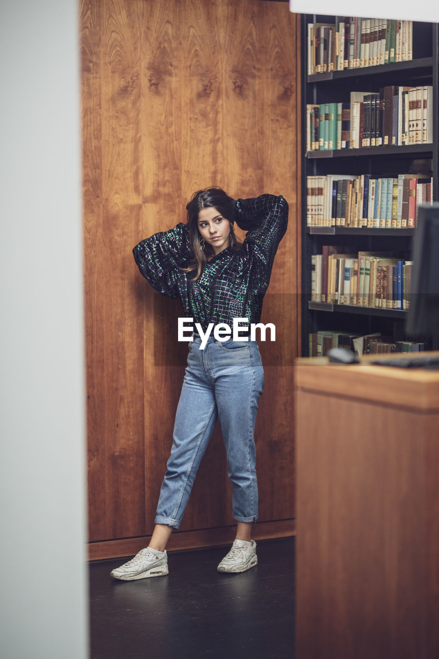 Full length of young woman standing at library