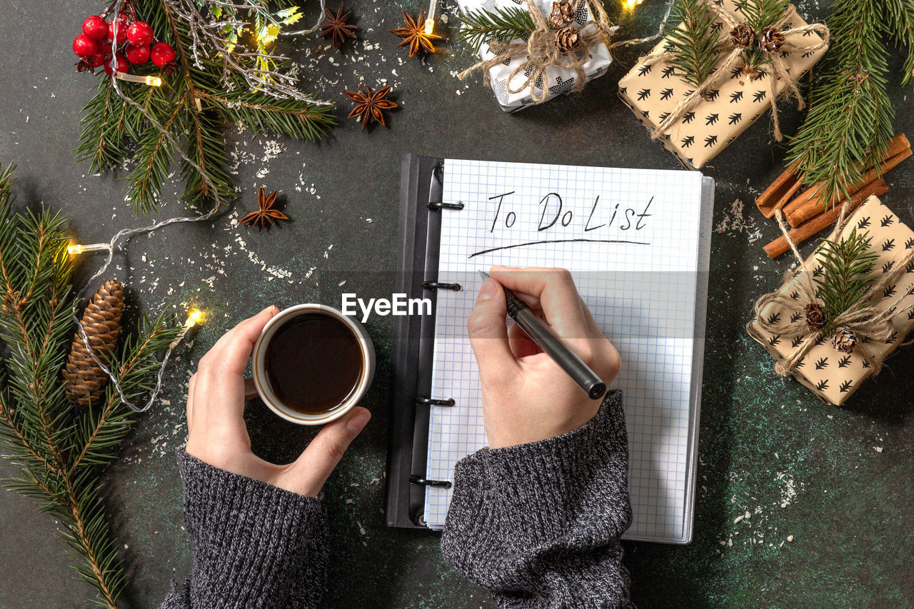 The woman writes in notebook with empty to do list and cup of coffee on xmas dark stone tabletop. 