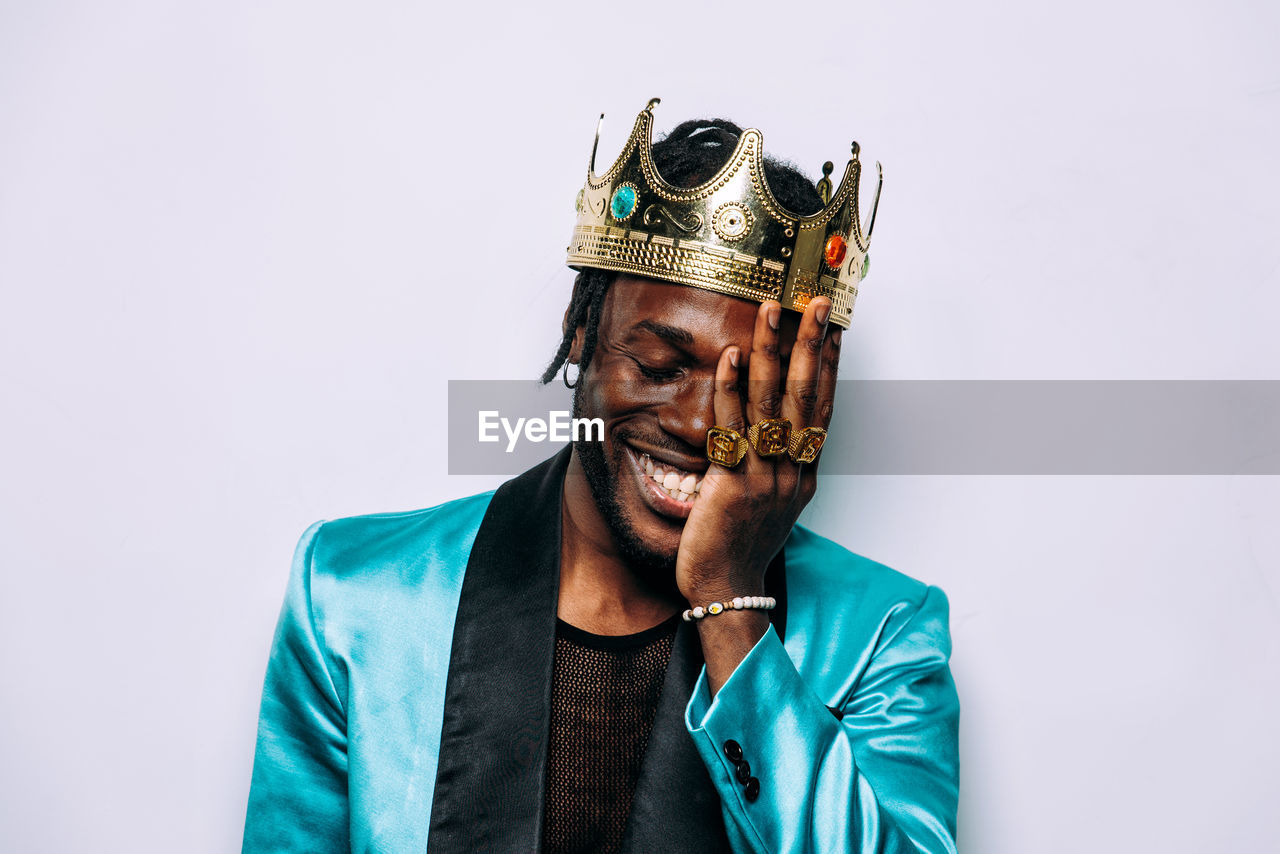 Smiling man wearing crown against white background