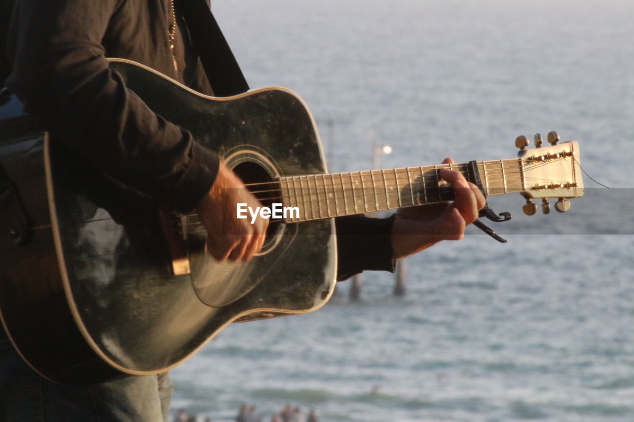 Close-up of man playing guitar at beach