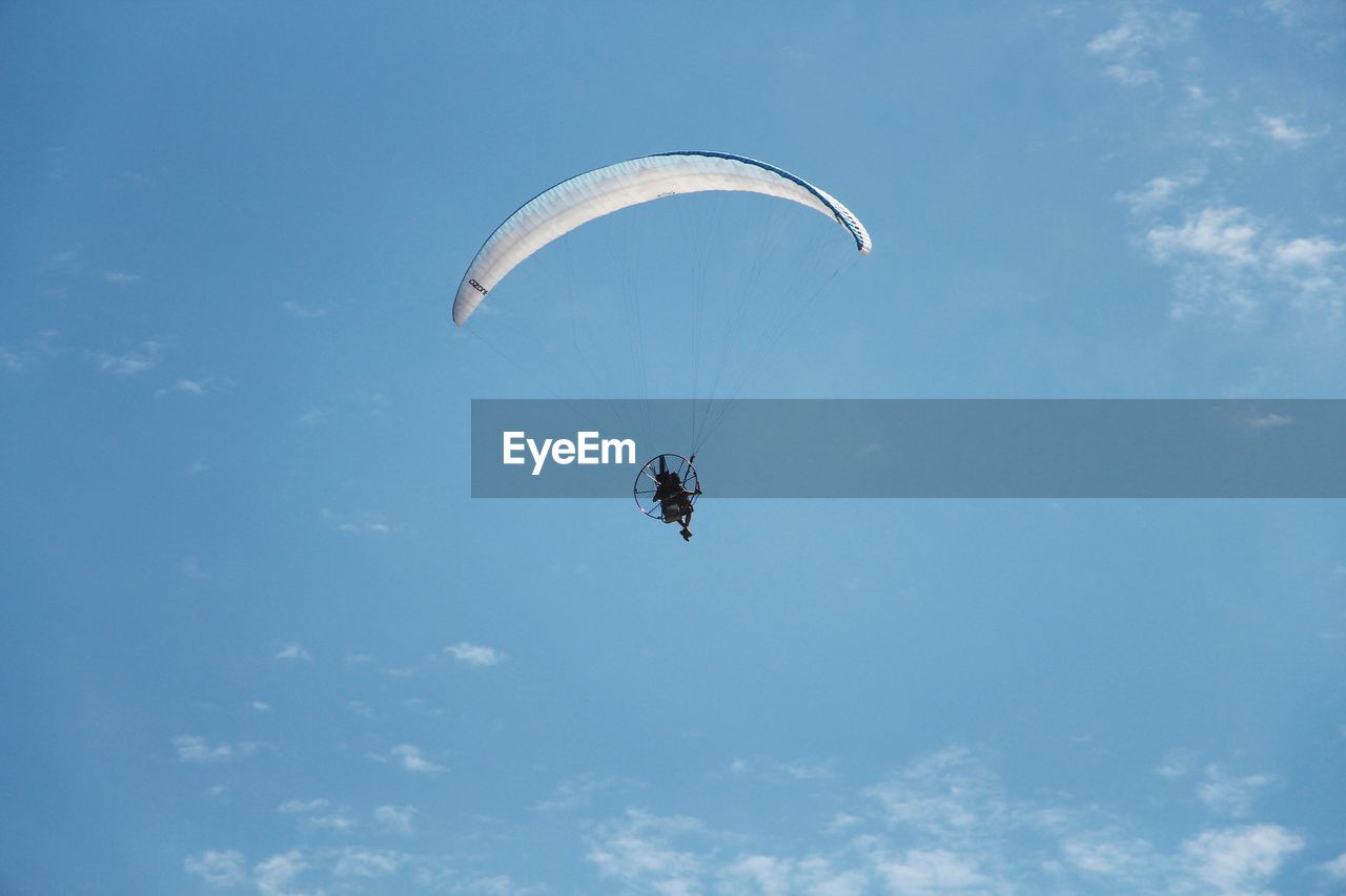 Low angle view of person paragliding against sky