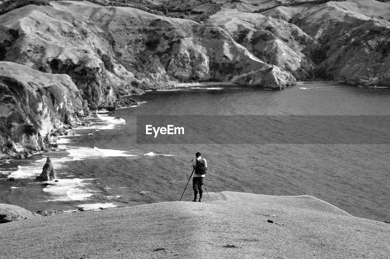 Rear view of photographing rocky sea shore