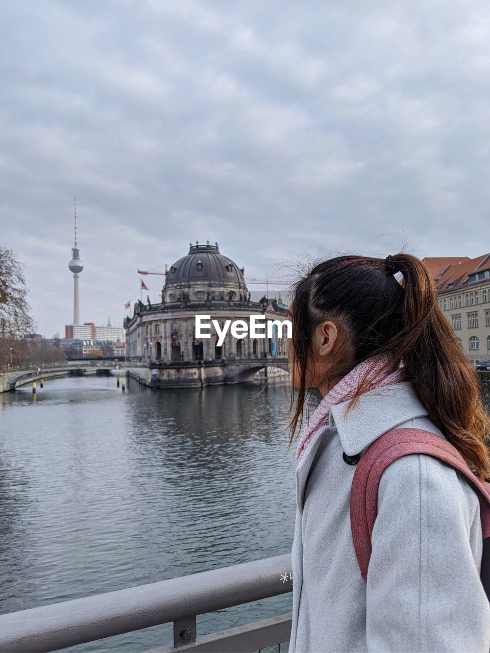 Rear view of woman overlooking river against cloudy sky