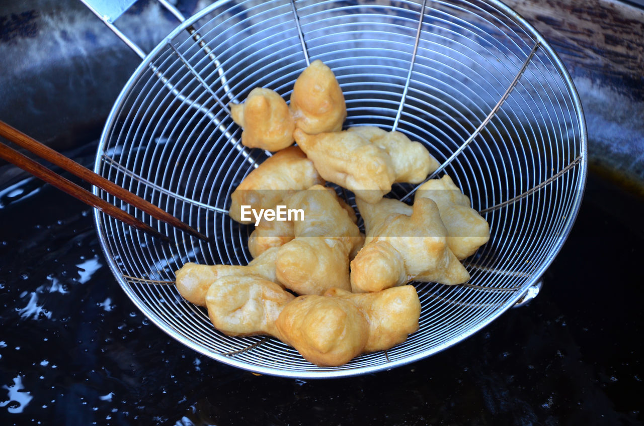 High angle view of food in strainer over wok