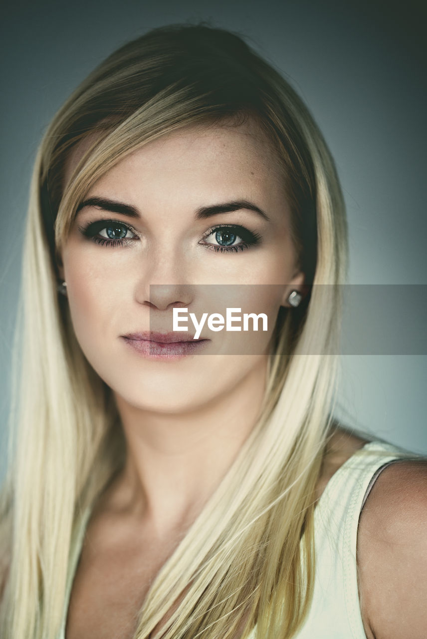 Close-up portrait of beautiful woman against gray background