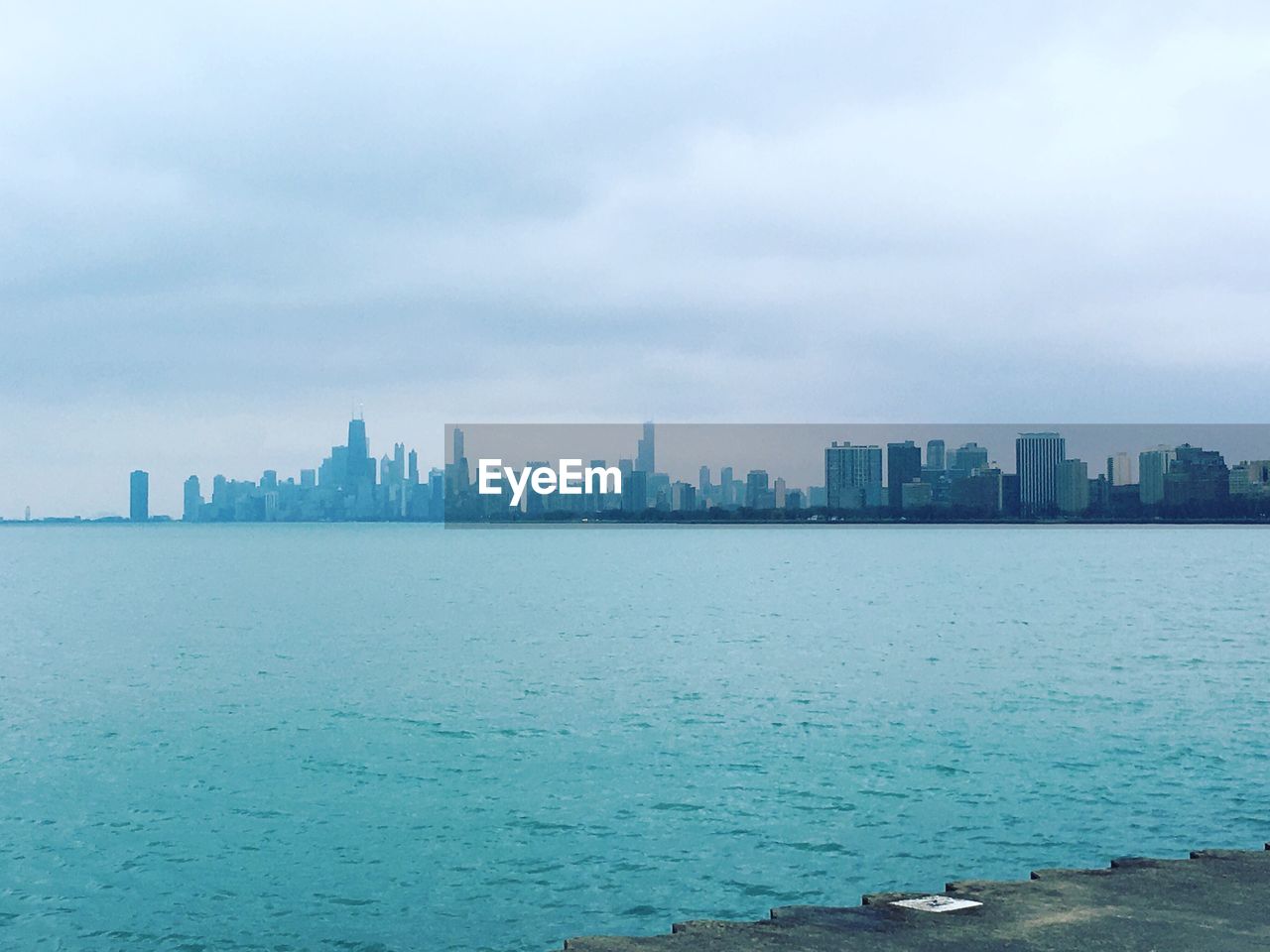 City skyline by sea against sky