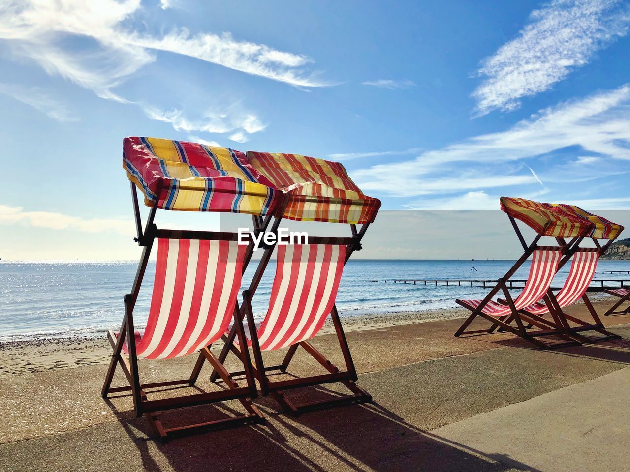 LOUNGE CHAIRS ON BEACH AGAINST SKY