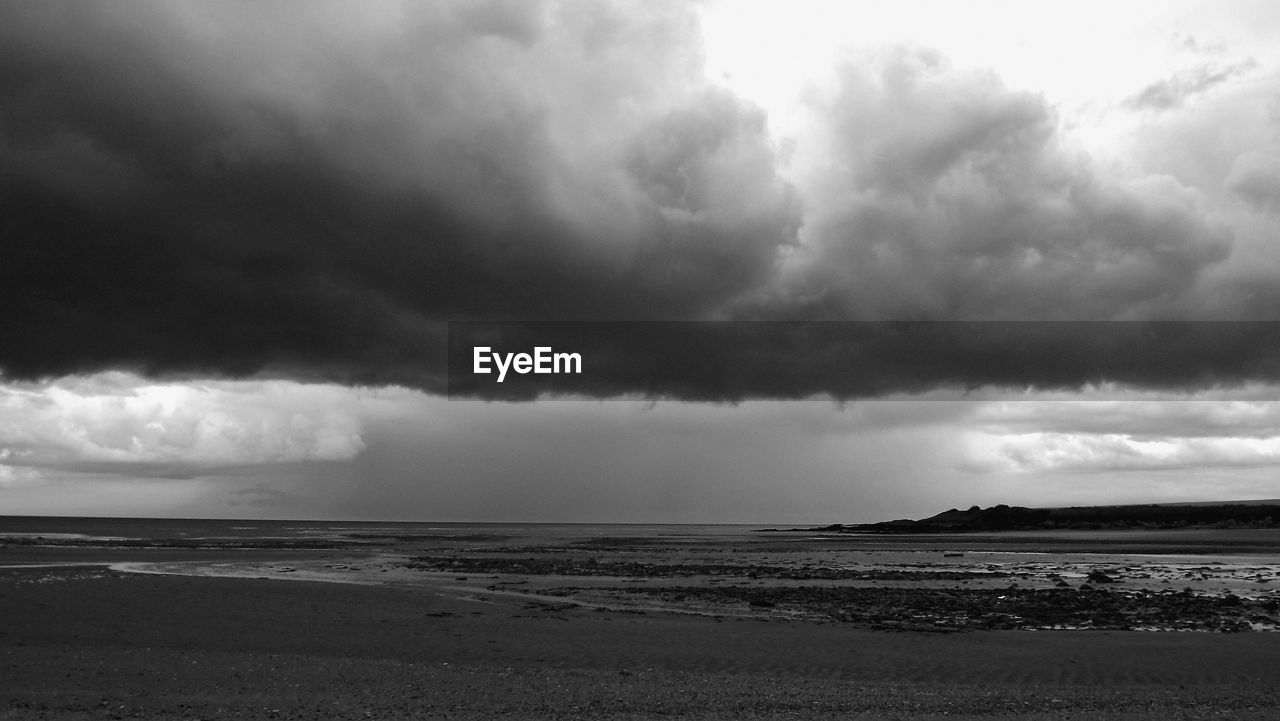 VIEW OF BEACH AGAINST CLOUDY SKY