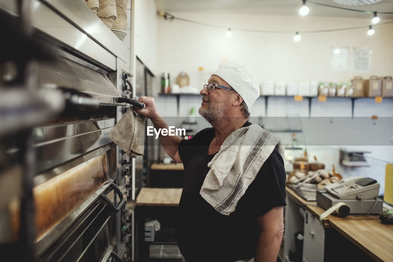Senior baker standing by oven at bakery