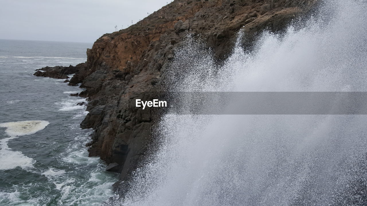 SCENIC VIEW OF SEA WAVES SPLASHING ON ROCKS