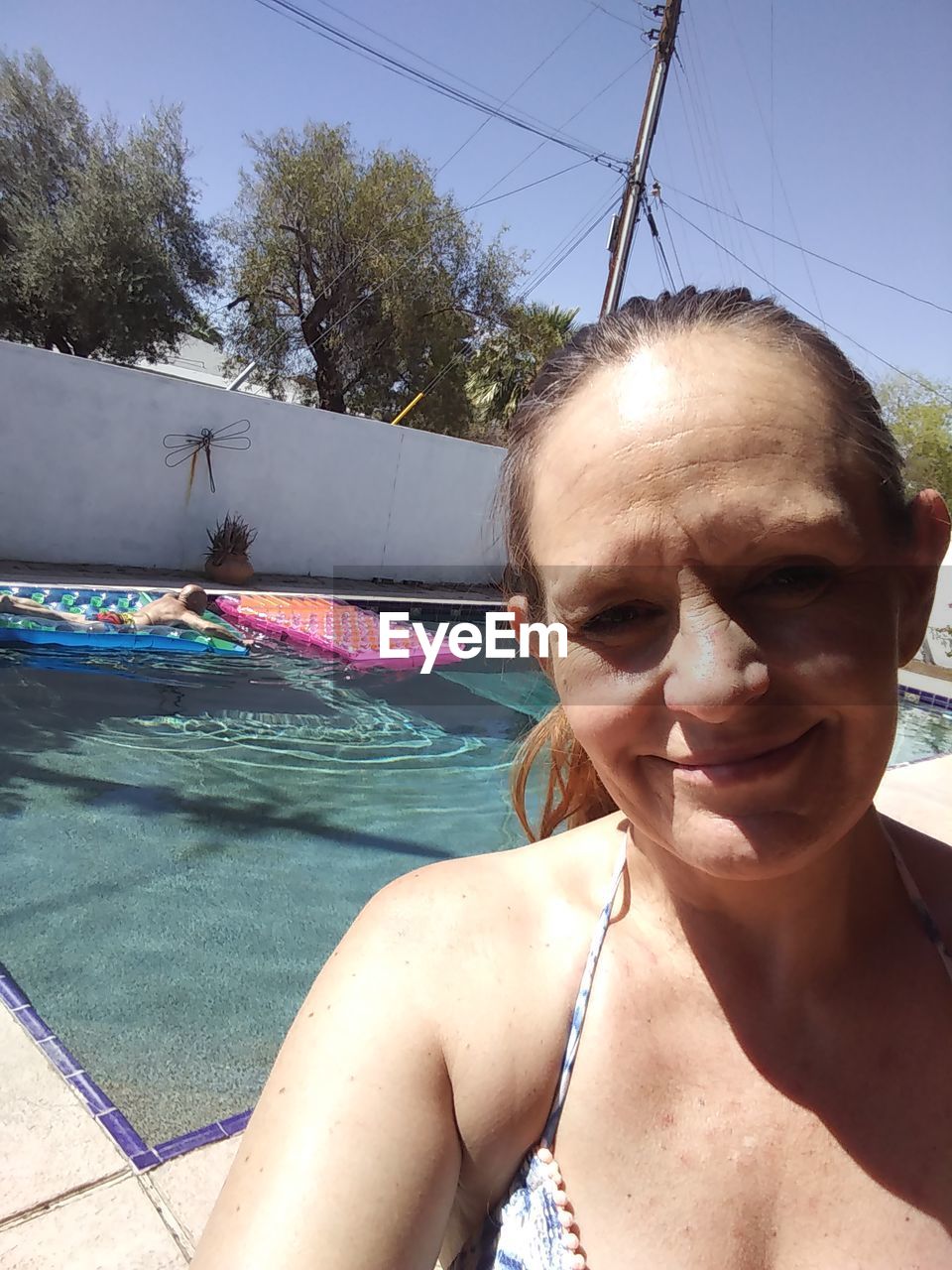 PORTRAIT OF A SMILING YOUNG WOMAN IN SWIMMING POOL