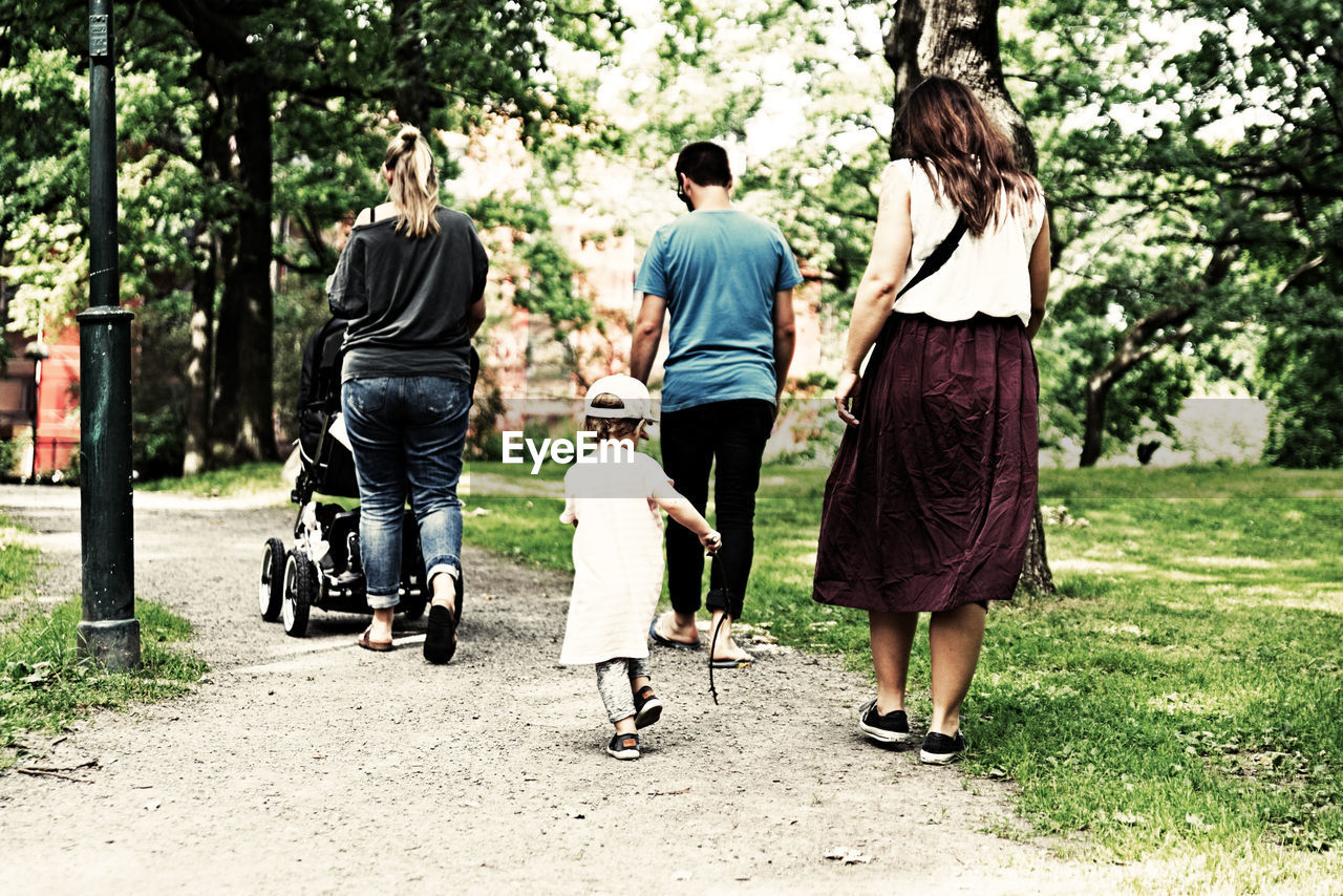 REAR VIEW OF PEOPLE WALKING ON PATHWAY