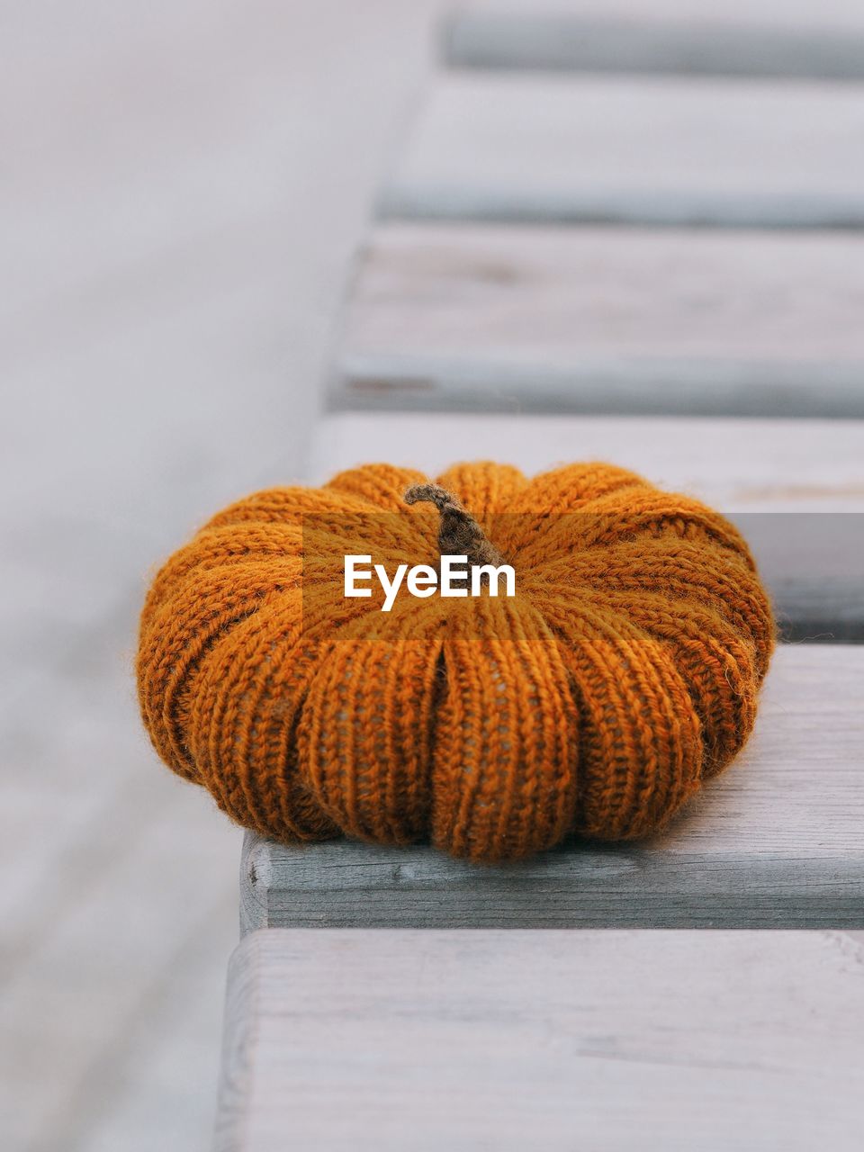 Knitted orange pumpkin on a wooden table.